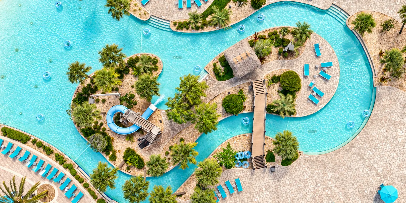 Aerial view of the lazy river, waterslide and palm-lined pools at The Retreat at ChampionsGate